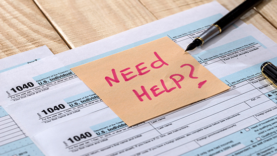 Tax forms with "Need Help?" on a post-it note